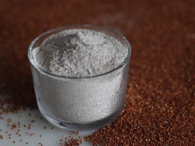 Ragi flour in a glass bowl along with a scattered spread of ragi grains around. Ingredients of ragi malt and many easy to cook recipe with finger millet for Health and wellness concept.